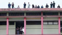 Penonton menyaksikan pertandingan antara Arema FC melawan PSM Makassar dari atap asrama Kepolisan pada laga BRI Liga 1 di Stadion PTIK, Jakarta, Sabtu (4/2/2023). PSM Makassar menang dengan skor 1-0. (Bola.com/M Iqbal Ichsan)