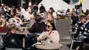 Orang-orang menikmati minuman sambil duduk di teras setelah lebih dari dua bulan penutupan karena pandemi Covid-19 di Helsinki (1/6/2020). (AFP Photo/Alessandro Rampazzo)