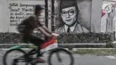 Pesepeda melintasi mural bergambar sosok Bung Hatta di Jalan Pluit Raya III, Jakarta, Minggu (10/8/2020). Mural itu diharapkan menjadi media agar masyarakat selalu mengingat sejarah dan menghargai jasa para pahlawan dalam memerdekakan Tanah Air. (merdeka.com/Iqbal Nugroho)