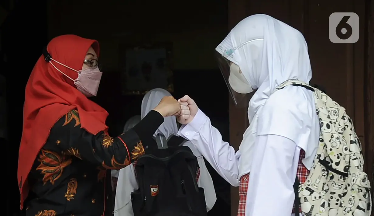 Salam hormat murid kepada guru saat pembelajaran tatap muka (PTM) terbatas di SDN Pisangan Baru 05 Pagi, Jakarta, Senin (8/11/2021). Penerapan protokol kesehatan dilakukan guna mencegah penyebaran COVID-19, terlebih belum adanya vaksinasi untuk anak usia 6-11 tahun. (merdeka com/Iqbal S. Nugroho)