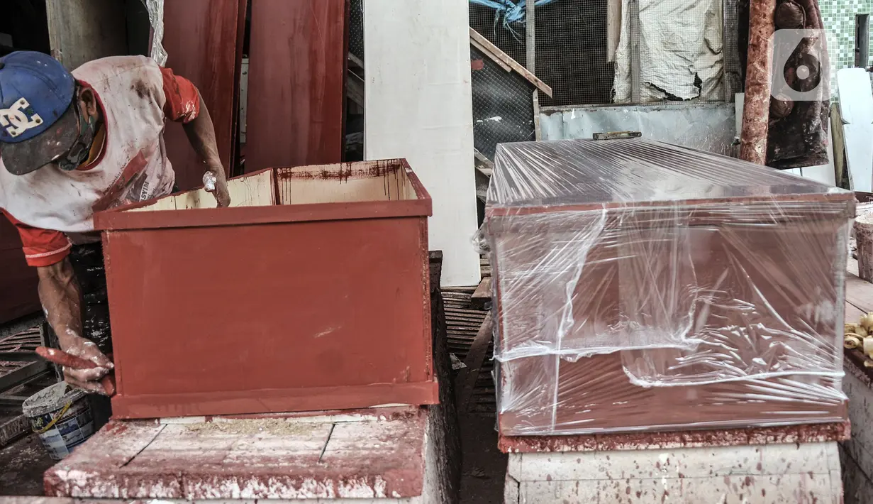 Pekerja menyelesaikan pembuatan peti jenazah untuk pasien Covid-19 di TPU Pondok Kelapa, Jakarta, Selasa (13/7/2021). Menurut pekerja, dalam sehari mampu membuat hingga 50 peti jenazah dari ratusan pesanan dari pihak rumah sakit, baik di Jakarta maupun luar kota. (merdeka.com/Iqbal S Nugroho)