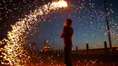 Seorang pemuda Palestina mengayunkan kembang api di depan sebuah masjid di Kota Gaza, Palestina (16/5). Mereka bermain kembang api untuk menyambut puasa pertama di bulan Ramadan. (AFP Photo/Mohammed Abed)