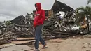 Seorang pria melewati reruntuhan gedung pemerintah yang rusak akibat gempa bumi di Mamuju, Sulawesi Barat, Sabtu (16/1/2021). Jalan dan jembatan rusak, pemadaman listrik, dan kurangnya alat berat menghambat evakuasi korban gempa magnitudo 6,2 SR yang melanda Majene- Mamuju (AP Photo/Joshua Marunduh)