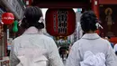 Dua wanita mengenakan yukata, pakaian musim panas tradisional Jepang mengunjungi kuil Buddha Sensoji di distrik Asakusa Tokyo (12/8/2021). Menurut urutan tingkat formalitas, yukata adalah kimono nonformal yang dipakai pria dan wanita pada kesempatan santai di musim panas. (AFP/David Gannon)
