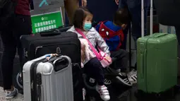 Seorang anak mengenakan masker duduk di antara koper-koper di Bandara Internasional Hong Kong di Hong Kong, Selasa (21/1/2020). Masker terjual habis dan pemeriksaan suhu di bandara dan stasiun kereta api menjadi norma baru di China menyusul merebaknya wabah virus corona.  (AP/Ng Han Guan)