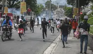 Para pengunjuk rasa dibubarkan oleh gas air mata yang dilemparkan oleh polisi selama demonstrasi menuntut Perdana Menteri Haiti Ariel Henry mundur dan menyerukan kualitas hidup yang lebih baik, di Port-au-Prince, Haiti, Senin (29/8/2022). (AP Photo/Odelyn Joseph)