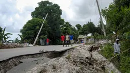 Warga berjalan di jalan yang rusak, empat hari setelah gempa berkekuatan 7,2 melanda bagian barat daya negara itu, di Rampe, Haiti, Rabu (18/8/2021). Korban jiwa akibat gempa bumi dahsyat yang melanda Haiti Sabtu pekan lalu terus bertambah menjadi 1.941 orang. (AP/Matias Delacroix)