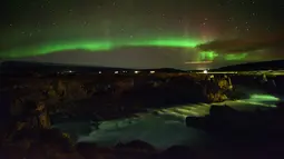 Langit berhias aurora borealis atau Cahaya Utara terlihat di atas Thingeyjarsveit dan sungai Sprengisandur di Islandia, 14 Oktober 2018. Aurora borealis selalu terjadi di antara September dan Oktober; dan Maret dan April. (Mariana SUAREZ/AFP)