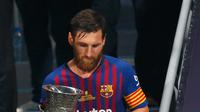 Penyerang Barcelona, Lionel Messi membawa Piala Super Spanyol usai mengalahkan Sevilla di Tangier, Maroko, (13/8). Barcelona meraih gelar ke-13 di Piala Super Spanyol terbanyak ketimbang tim lain. (AP Photo/Mosa'ab Elshamy)