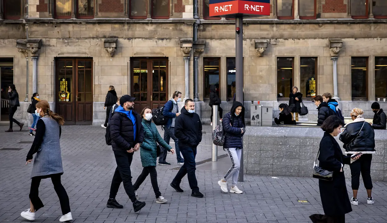 Orang-orang dengan masker berjalan di Stasiun Pusat Amsterdam, Belanda, Rabu (3/11/2021). Belanda kembali menerapkan tindakan pembatasan virus corona, termasuk kewajiban memakai masker di berbagai ruang publik menyusul lonjakan kasus Covid-19 beberapa waktu terakhir. (Ramon van Flymen/ANP/AFP)