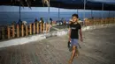Yousef Al-Bahtini berjalan di tepi pantai di pelabuhan Kota Gaza (20/9). Bocah Palestina ini siap memecahkan waktu tercepat rekor Guinness World Records dengan melakukan perjalanan 20 meter dalam kelenturan tubuh. (AFP Photo/Mohammed Abed)
