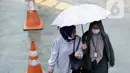 Pekerja menggunakan payung saat melintasi ruas jalan di kawasan Kuningan, Jakarta, Kamis (18/12/2021). BMKG memprakirakan potensi hujan lebat yang mungkin disertai petir dan angin kencang hingga 21 Februari di beberapa provinsi di Indonesia, termasuk DKI Jakarta. (Liputan6.com/Helmi Fithriansyah)