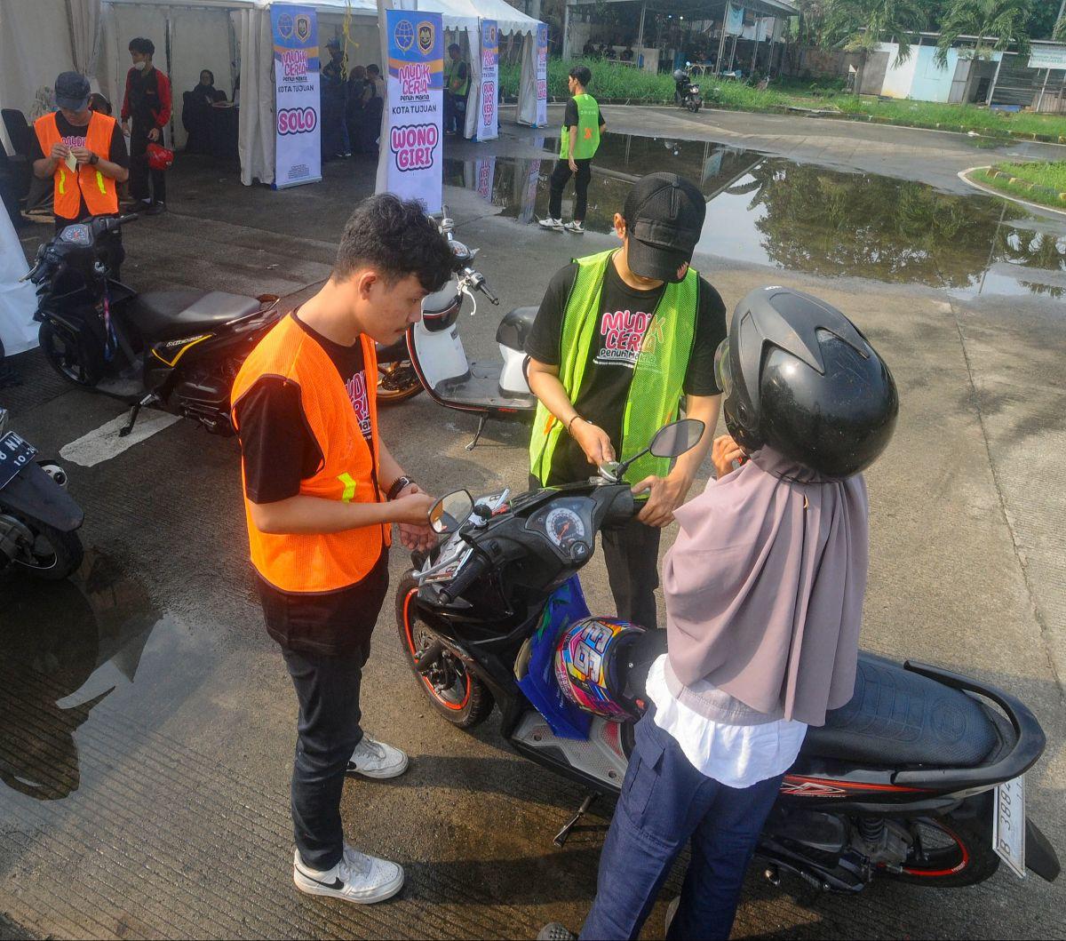 Peserta mengantarkan sepeda motornya yang akan diberangkatkan ke kampung halaman dalam program mudik gratis Kemenhub di&nbsp;Terminal Pondok Cabe, Tangerang Selatan, Banten, Jumat (5/4/2024). Mudik gratis untuk pengendara sepeda motor ini  diselenggarakan