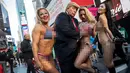 Seorang seniman berpenampilan seperti Donald Trump meraba-raba wanita seksi berbikini saat berada di depan Trump Tower di New York, 25 Oktober 2016. (AFP Photo/Drew Angerer/Getty Images)