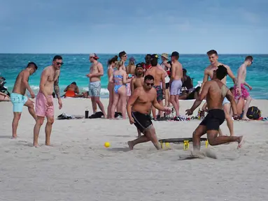 Orang-orang bersenang-senang di pantai di Miami, Florida pada Selasa (16/3/2021). Mahasiswa telah tiba di daerah Florida Selatan untuk liburan musim semi tahunan. Para pejabat kota prihatin dengan kerumunan liburan musim semi saat pandemi COVID-19 terus berlanjut. (Joe Raedle/Getty Images/AFP)