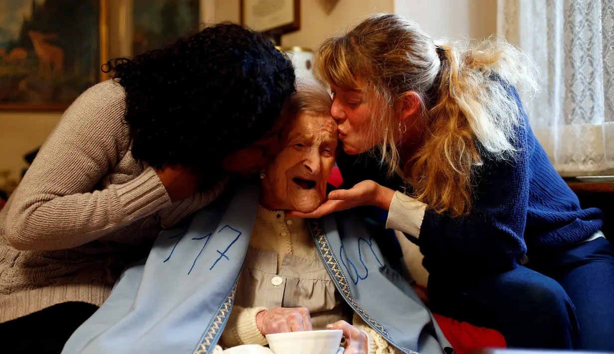Nenek Emma Morano mendapat ciuman oleh dua pengasuhnya Malgorzat Ceglinska dan Yamilec Vergara saat merayakan ulang tahun yang ke-117 di rumahnya di Verbania, Italia, (29/11). (REUTERS/Alessandro Garofalo)