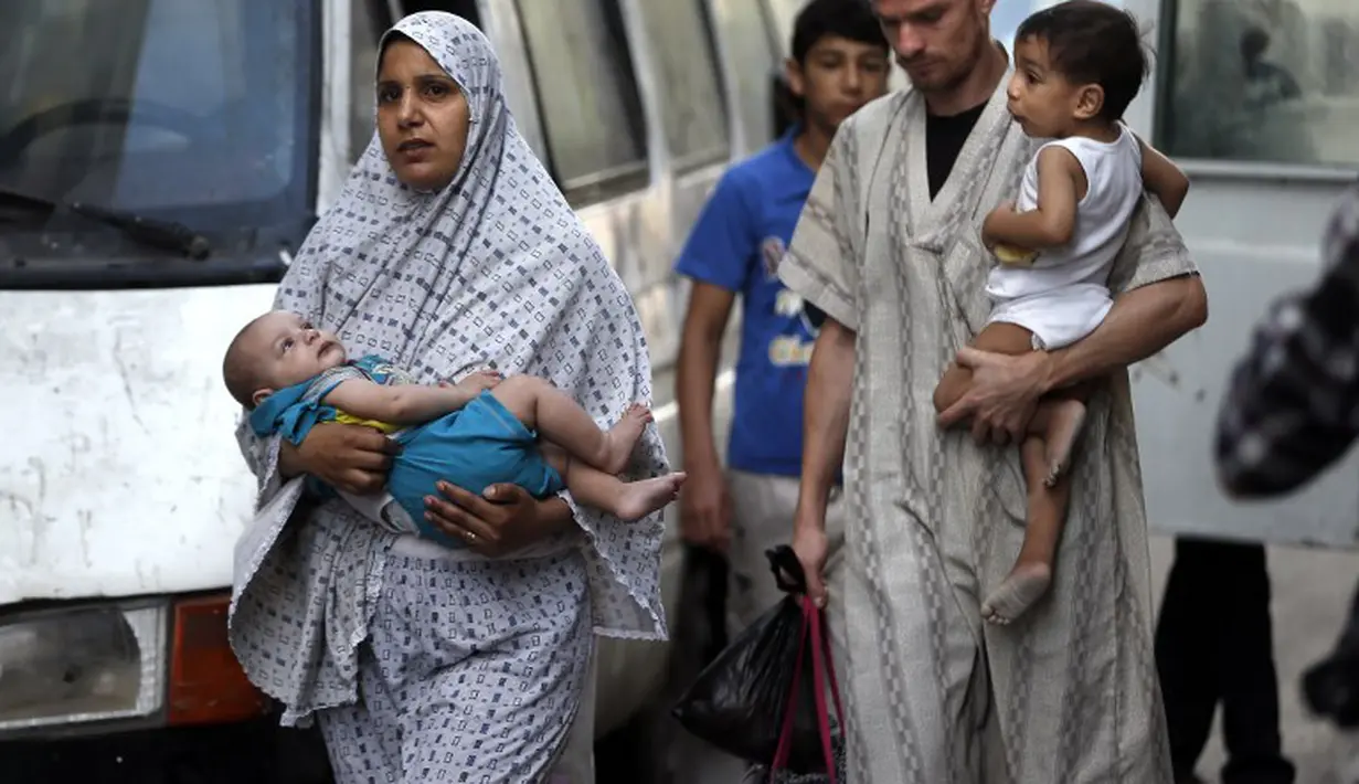 Sebuah keluarga Palestina meninggalkan rumah mereka setelah peringatan serangan Israel di Kota Gaza pada tanggal 15 Juli 2014 (AFP PHOTO/THOMAS COEX)
