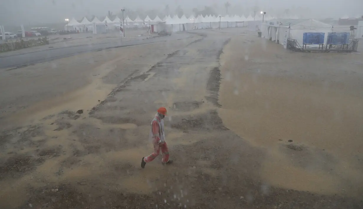 Seorang marshal berjalan saat hujan lebat sebelum Race 1 World Superbike (WSBK) di Pertamina Mandalika International Street Circuit, Lombok Tengah, Nusa Tenggara Barat, Sabtu (20/11/2021). Hujan deras memaksa Race 1 WSBK Mandalika ditunda pada 21 November. (AP Photo/Achmad Ibrahim)