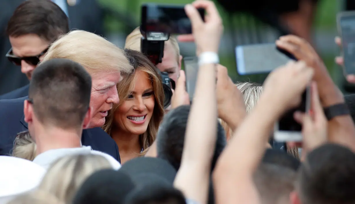 Presiden AS Donald Trump ditemani Melania Trump menyapa keluarga militer pada acara piknik di halaman Gedung Putih, Rabu (4/7). Setelah menjalani operasi ginjal, kesehatan Melania tampaknya telah membaik. (AP/Alex Brandon)