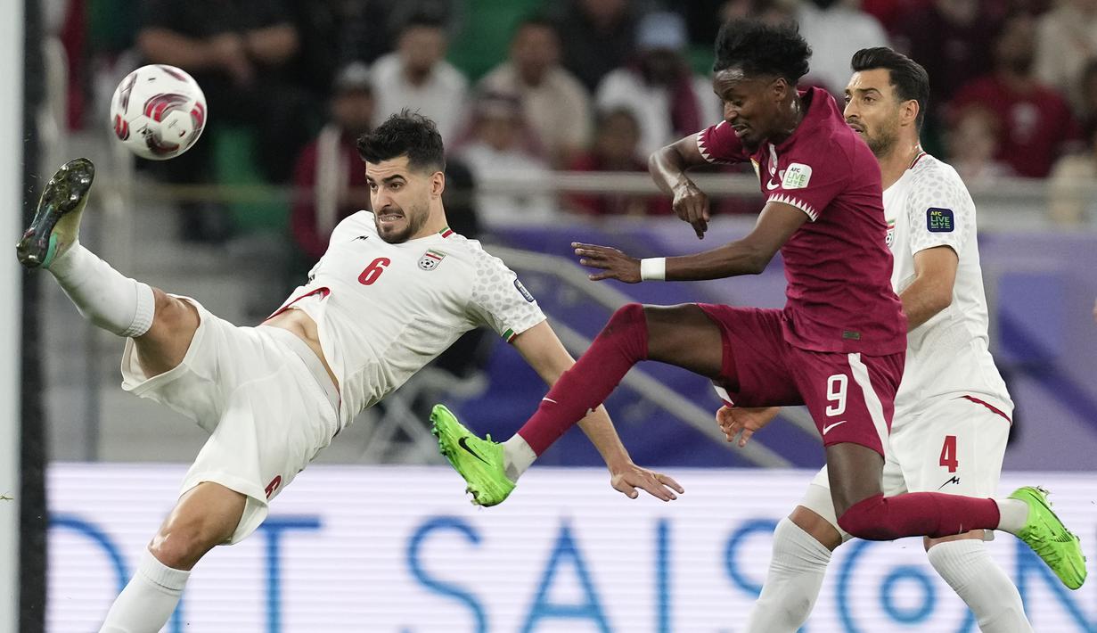 Pemain Iran, Saeid Ezatolahi (kiri) menendang bola dibayangi pemain Qatar, Yusuf Abdurisag pada laga semifinal Piala Asia 2023 di Al Thumama Stadium, Doha, Qatar, Rabu (07/02/2024). (AP Photo/Thanassis Stavrakis)