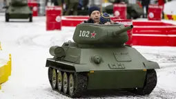 Seorang anak ditemani seorang pria mengendarai model tank T-34 era Soviet yang legendaris di objek wisata petualangan anak-anak Tankodrom di taman Sokolniki di Moskow, Rusia (6/1/2020). Perlombaan dengan menggunakan tank ini dikenai biaya sekitar US $ 6,5 AS. (AP Photo/Alexander Zemlianichenko)