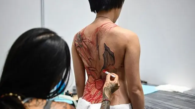 Seorang seniman tato bekerja pada klien selama International Malaysia Tattoo Expo di Kuala Lumpur.