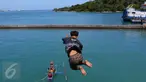 Seorang anak melompat ke laut ketika penumpang melemparkan koin dari atas kapal di Pelabuhan Merak, Banten, Jumat (26/8). Aksi anak-anak pemburu koin itu menjadi hiburan bagi penumpang yang akan menyeberang ke Pulau Sumatera. (Liputan6.com/Angga Yuniar)