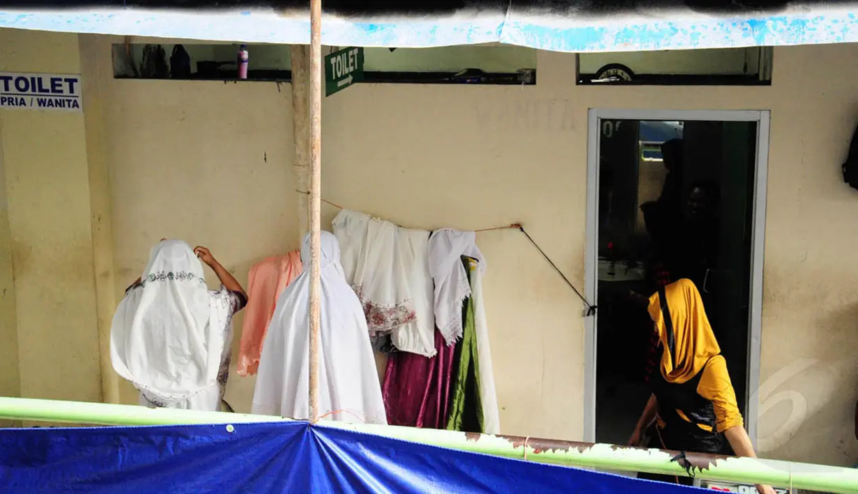 Dua orang pedagang wanita terlihat tengah bersiap untuk sholat di depan toilet umum di Pasar Blok G, Tanah Abang, Jakarta, (8/7/2014). Mereka beralasan karena lebih dekat dengan lokasi mereka berjualan (Liputan6.com/ Faizal Fanani)
