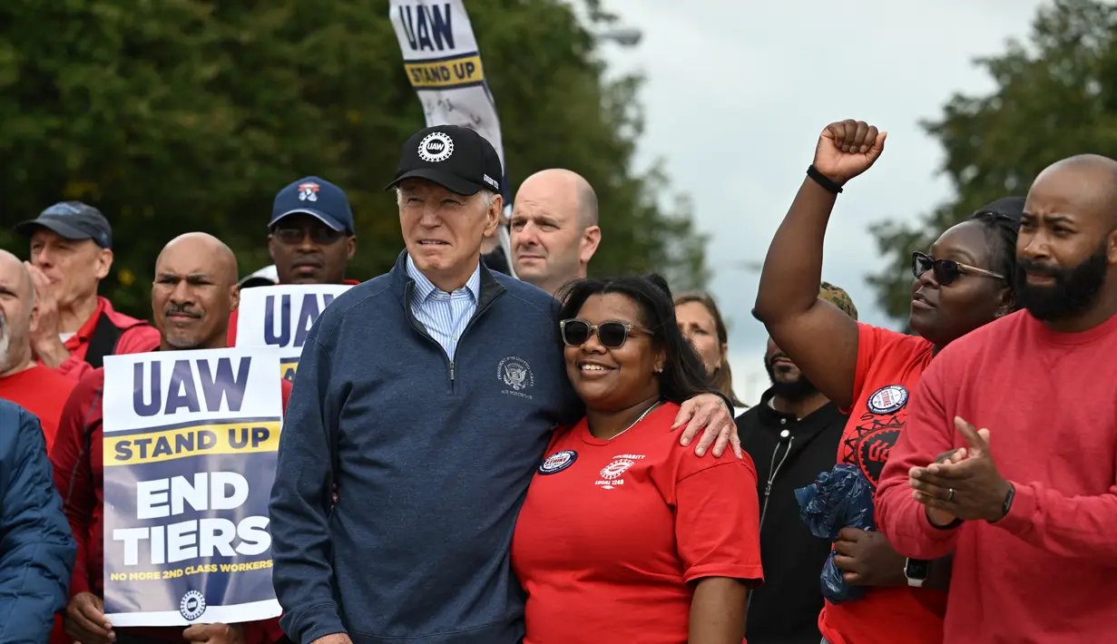 Joe Biden berdiri di sebelah para pekerja otomotif yang berunjuk rasa di Michigan. (Photo by Jim WATSON / AFP)