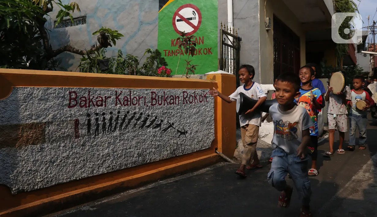 Anak-anak melintasi mural bertema bebas asap rokok di lingkungan RW 06 Kelurahan Kayu Manis, Matraman, Jakarta, Jumat (8/10/2021). Warga sejumlah RT di RW 06 berkomitmen menjaga lingkungan dari asap rokok dengan memberikan teguran dan sanksi bagi yang melanggar. (Liputan6.com/Herman Zakharia)