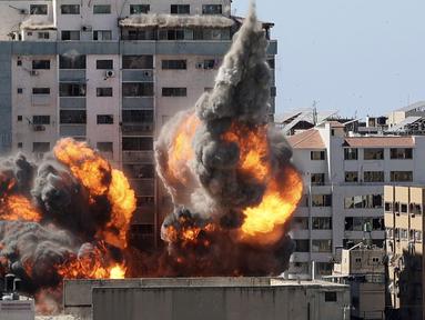 Bola api meletus dari gedung yang menampung berbagai media internasional, termasuk The Associated Press, setelah serangan udara Israel di Kota Gaza, Sabtu (15/5/2021). Serangan terjadi satu jam usai militer Israel memerintahkan orang-orang untuk mengungsi dari gedung. (Mahmud Hams/Pool Photo via AP)