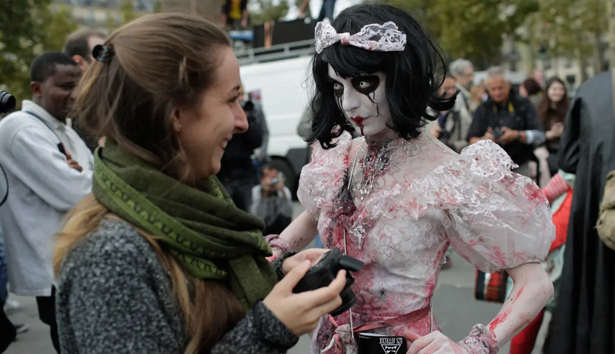 Seorang wanita mengenakan gaun berinteraksi dengan pengunjung saat "Zombie Walk" di Paris, Prancis (7/10). Dalam festival ini peserta berdandan dan mengenakan kostum layaknya zombie. (AFP Photo/Thomas Samson)