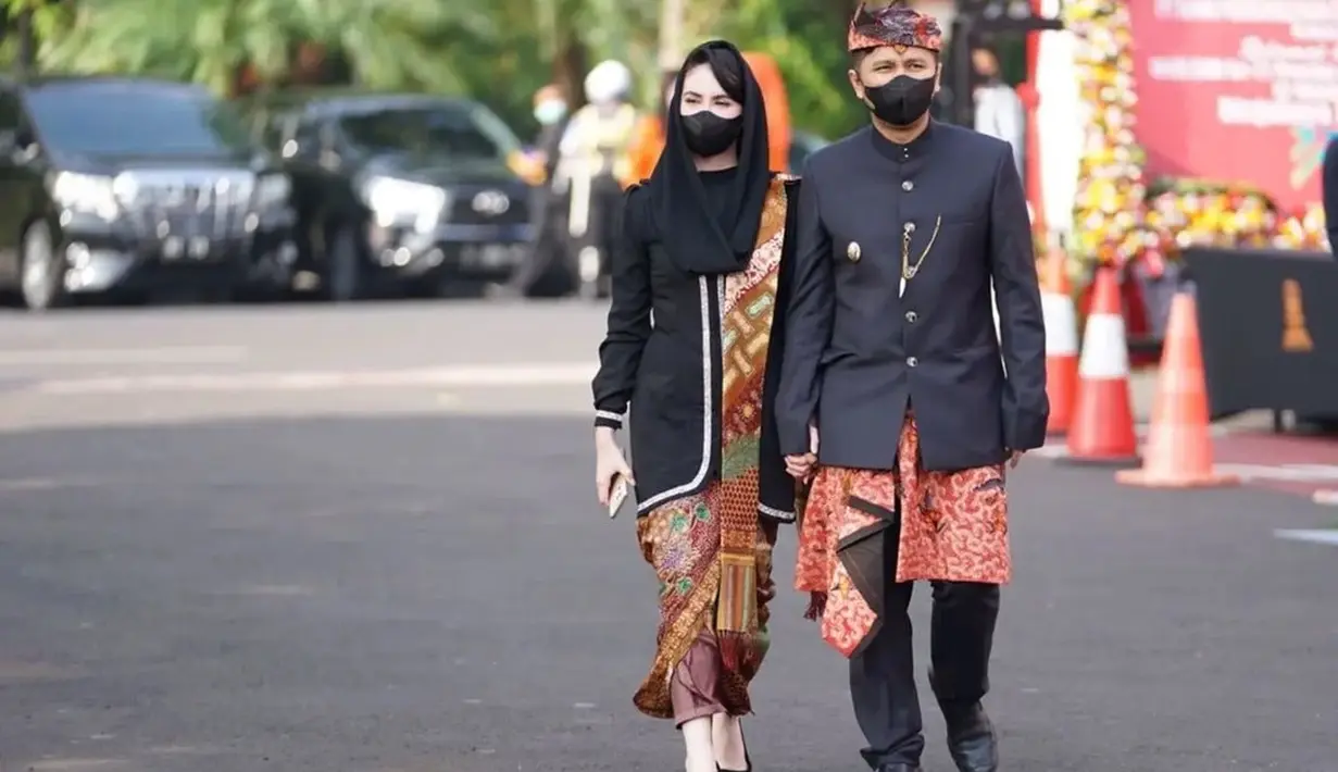 Mendampingi sang suami bertugas dengan gaya ikonisnya sebagai istri pejabat, Arumi Bachsin tampil elegan. Ia gunakan kebaya hitam polos dengan sentuhan selendang batik dan rok dari kain batik yang serasi. Rambutnya ditutup dengan selendang hitam polos, menampilkan poni rapi yang ditata ke samping. [Foto: Instagram/arumibachsin_94]