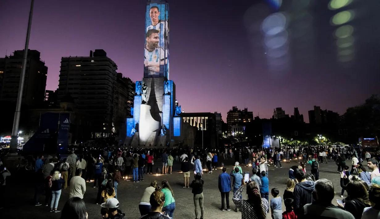 Video mapping memperlihatkan gambar bintang sepak bola Argentina Lionel Messi dan Angel Di Maria di "Monumento Nacional a la Bandera" di Rosario, Senin (21/11/2022). Proyeksi cahaya tersebut sebagai bentuk untuk menyemangati timnas Argentina sebelum menghadapi Arab Saudi dalam laga pertama Grup C Piala Dunia 2022, Selasa (22/11/2022) petang WIB. (Marcelo Manera / AFP)