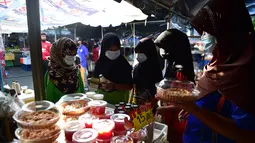 Sejumlah wanita mengenakan masker di pasar, sebagai bagian dari upaya untuk menghentikan penyebaran virus corona Covid-19, selama bulan suci Ramadhan di provinsi selatan Thailand, Narathiwat (17/4/2021). (AFP/Madaree Tohlala)
