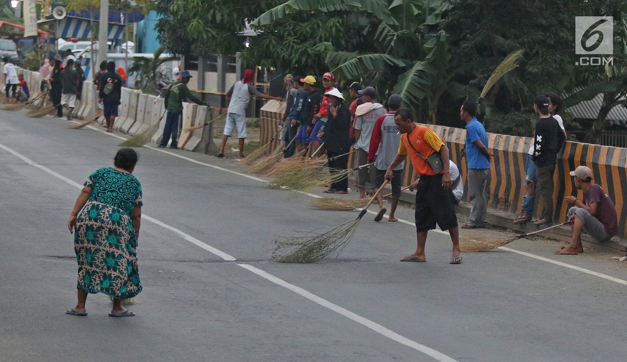 Warga berebut uang yang dilemparkan pengguna jalan menggunakan sapu di Jembatan Sewo, Indramayu, Jawa Barat, Senin (3/6/2019). Kehadiran pencari sedekah tersebut biasanya kian bertambah banyak saat menjelang arus mudik Lebaran. (Liputan6.com/Herman Zakharia)
