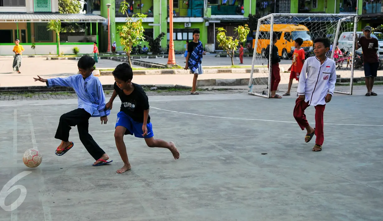 Dua anak berebut bola saat bermain futsal di lapangan Rusun Muara Kapuk, Jakarta, Jumat (22/4/2016). Rusun Muara Kapuk sediakan fasilitas lapangan sebagai sarana bermain untuk anak-anak. (Liputan6.com/Yoppy Renato)