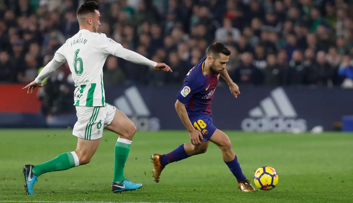Pemain Barcelona, Jordi Alba berebut bola dengan pemain Real Betis, Fabian pada pertandingan lanjutan La Liga di Stadion Benito Villamarin, Minggu (21/1). Barcelona menang telak 5-0 atas tuan rumah Real Betis. (AP/Miguel Morenatti)