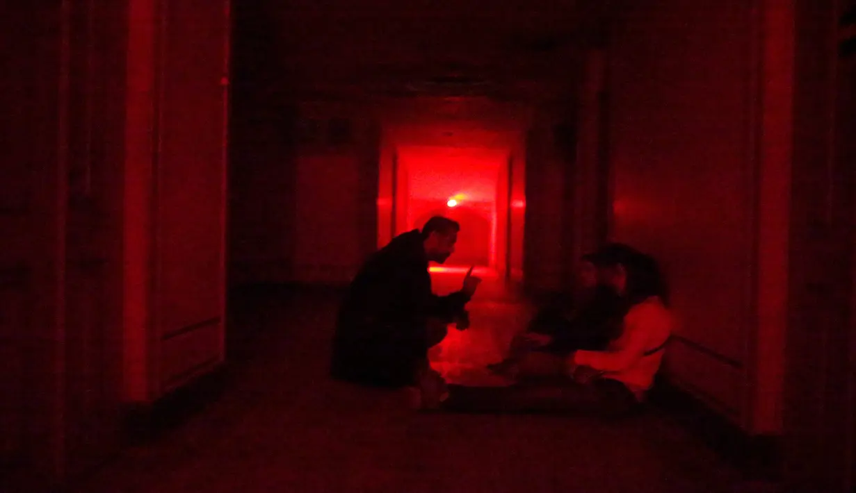 Pengunjung mendengarkan instruksi saat berada di dalam rumah hantu Quinta Nova da Assuncao di Belas, Portugal (13/5). Rumah hantu ini berisi 25 kamar dipenuhi penampakan bayangan dan suara dari pintu yang menutup secara acak. (REUTERS/Rafael Marchante)
