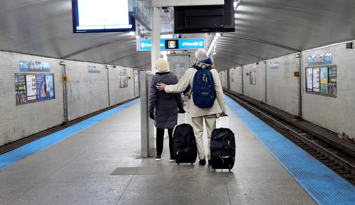 Pelancong naik Kereta L ke Bandara Internasional O'Hare di Chicago, Illinois (22/12/2022). Sistem cuaca musim dingin yang membawa salju, angin kencang, dan suhu di bawah nol telah mendatangkan malapetaka pada perjalanan liburan selama salah satu hari tersibuk dalam setahun untuk maskapai penerbangan. (Scott Olson/Getty Images/AFP)