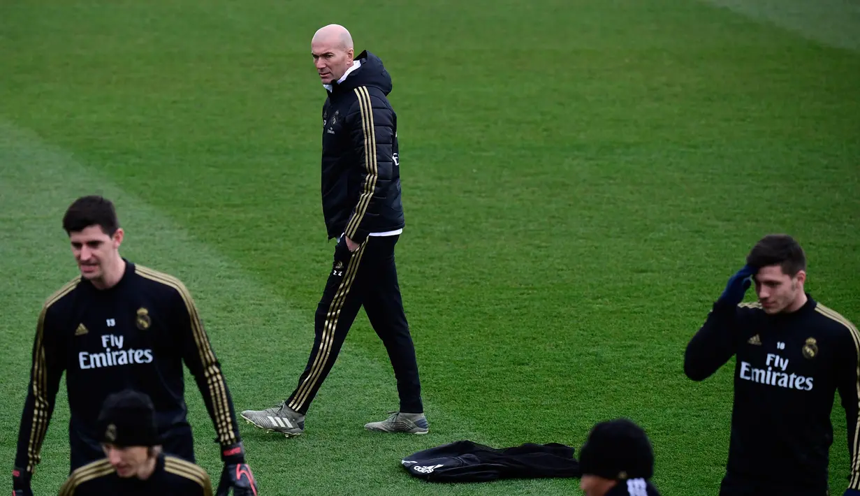Pelatih Real Madrid, Zinedine Zidane (tengah) melihat para pemainnya berlatih di fasilitas olahraga Real Madrid City di Madrid (17/12/2019). Real Madrid akan bertanding melawan Barcelona dalam laga El Clasico di Nou Camp. (AFP/Javier Soriano)