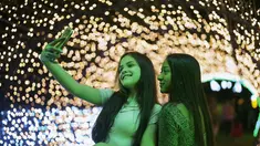 Dua wanita berfoto selfie di acara lampu Natal di taman Ibirapuera di Sao Paulo, Brasil, Selasa (14/12/2021). Jelang perayaan Natal, taman dan pantai dihiasi lampu-lampu yang indah. (AP Photo/Andre Penner)
