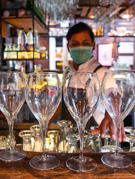 Bartender Gagan membersihkan bar jelang pembukaan kembali di New Delhi, 8 September 2020. Setelah sebelumnya ditutup karena pandemi COVID-19, mulai 9 September 2020 New Delhi mengizinkan bar kembali buka dengan kapasitas tempat duduk 50 persen. (Prakash SINGH/AFP)