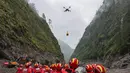 Sebuah drone membawa muatan melintasi udara saat operasi pencarian dan penyelamatan berlangsung di wilayah yang dilanda tanah longsor di Kabupaten Gyirong, Daerah Otonom Tibet, Tiongkok barat daya, Sabtu, 29 Agustus 2026. (Jiang Fan/Xinhua via AP)