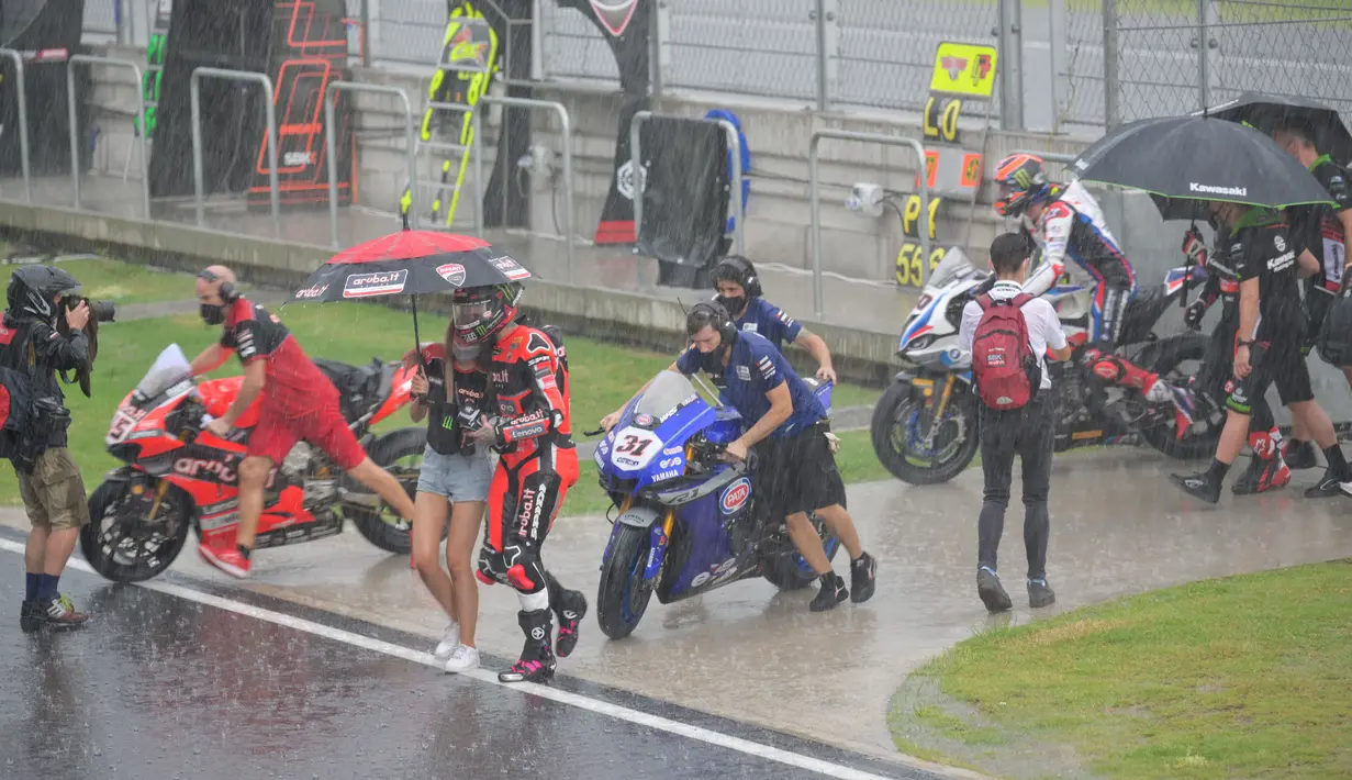 Pembalap dan kru berjalan menuju paddock saat hujan lebat sebelum Race 2 WSBK Mandalika 2021 di Pertamina Mandalika International Street Circuit, Lombok, Nusa Tenggara Barat, Minggu (21/11/2021). Balapan dilanjutkan pukul 15.30 WIB atau 16.30 Wita dan hanya digelar 12 lap. (BAY ISMOYO/AFP)