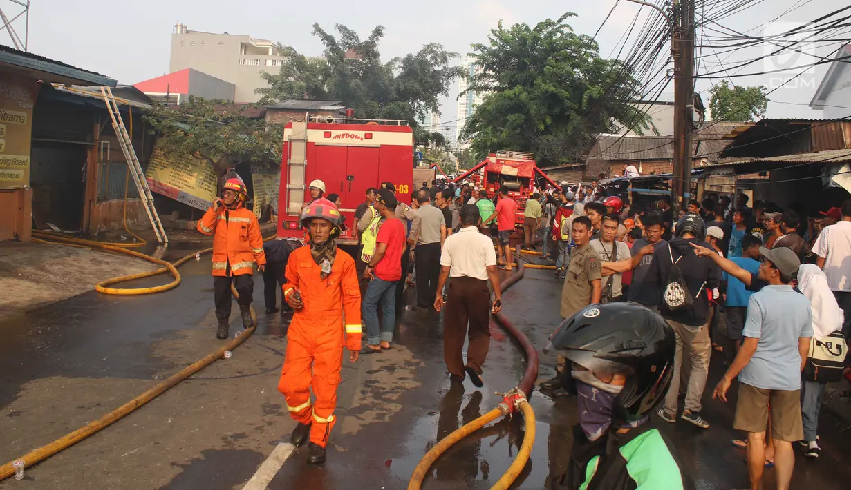 Sejumlah orang berkumpul melihat upaya pemadaman api yang membakar sebuah percetakan dan pabrik roti di Jalan Cawang Baru, Kavling Otista, Jakarta, Selasa (19/9). Kobakarn api tersebut telah menjalar di pemukiman padat penduduk (Liputan6.com/Angga Yuniar)
