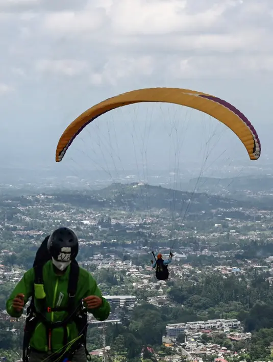 Seorang paraglider lepas landas dari lereng bukit di Puncak, Bogor, Jawa Barat, Kamis (2/12/2021). Destinasi wisata alam Bukit Paralayang Puncak Bogor sangat cocok untuk dikunjungi pada liburan akhir pekan bersama keluarga, sahabat maupun pasangan tercinta. (Goh Chai Hin/AFP)
