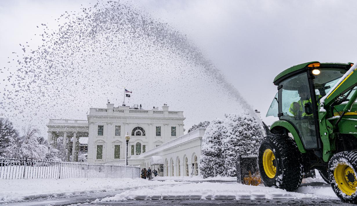 Penjaga halaman membersihkan jalan masuk di depan West Wing Gedung Putih di Washington, saat badai musim dingin bertiup ke wilayah Atlantik Tengah pada Senin (3/1/2022) dini hari. Hujan salju lebat disertai angin kencang mengguyur wilayah tenggara dan tengah Amerika Serikat. (AP Photo/Andrew Harnik)