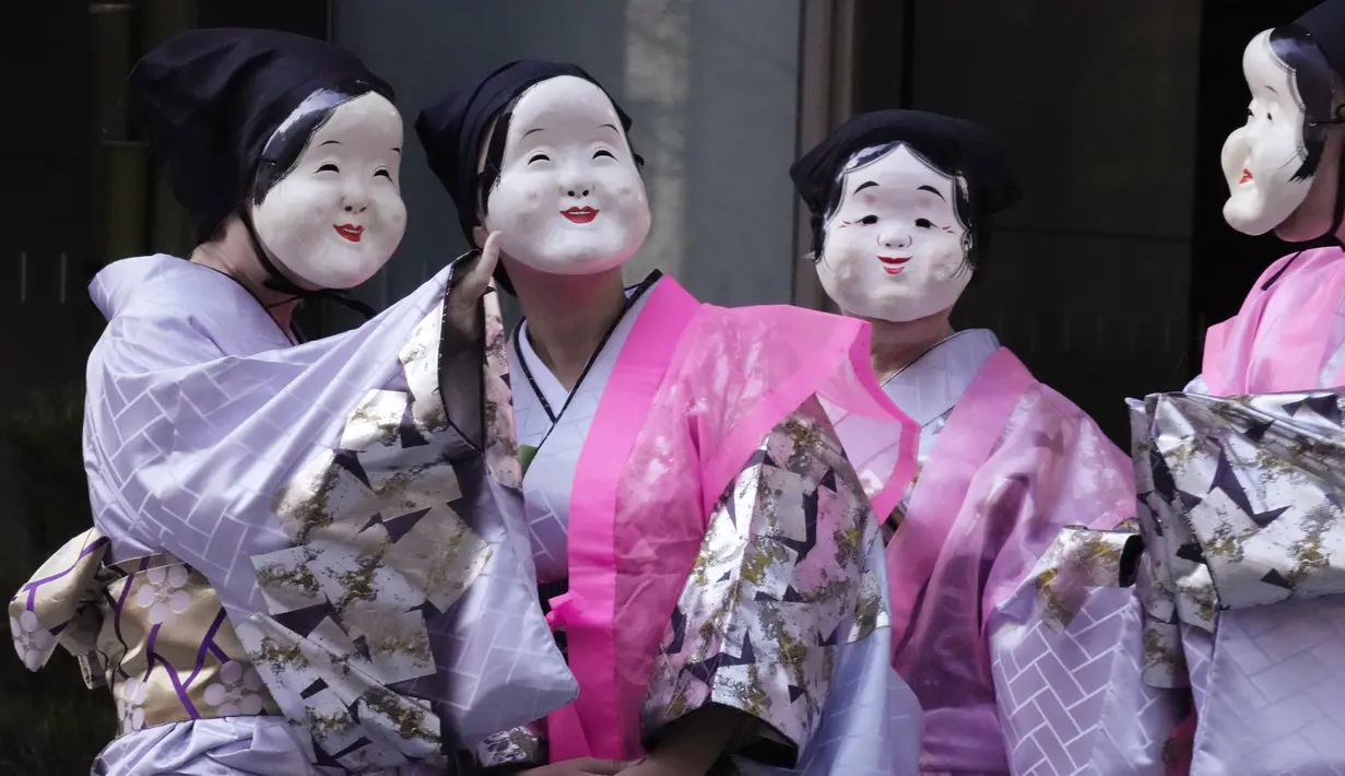 Seniman yang mengenakan topeng Otafuku atau Okame tradisional Jepang bersiap untuk berpartisipasi dalam Festival Konpira di kuil Kotohiragu di distrik bisnis Toranomon, Tokyo, Selasa (10/1/2023).  (AP Photo/Eugene Hoshiko)