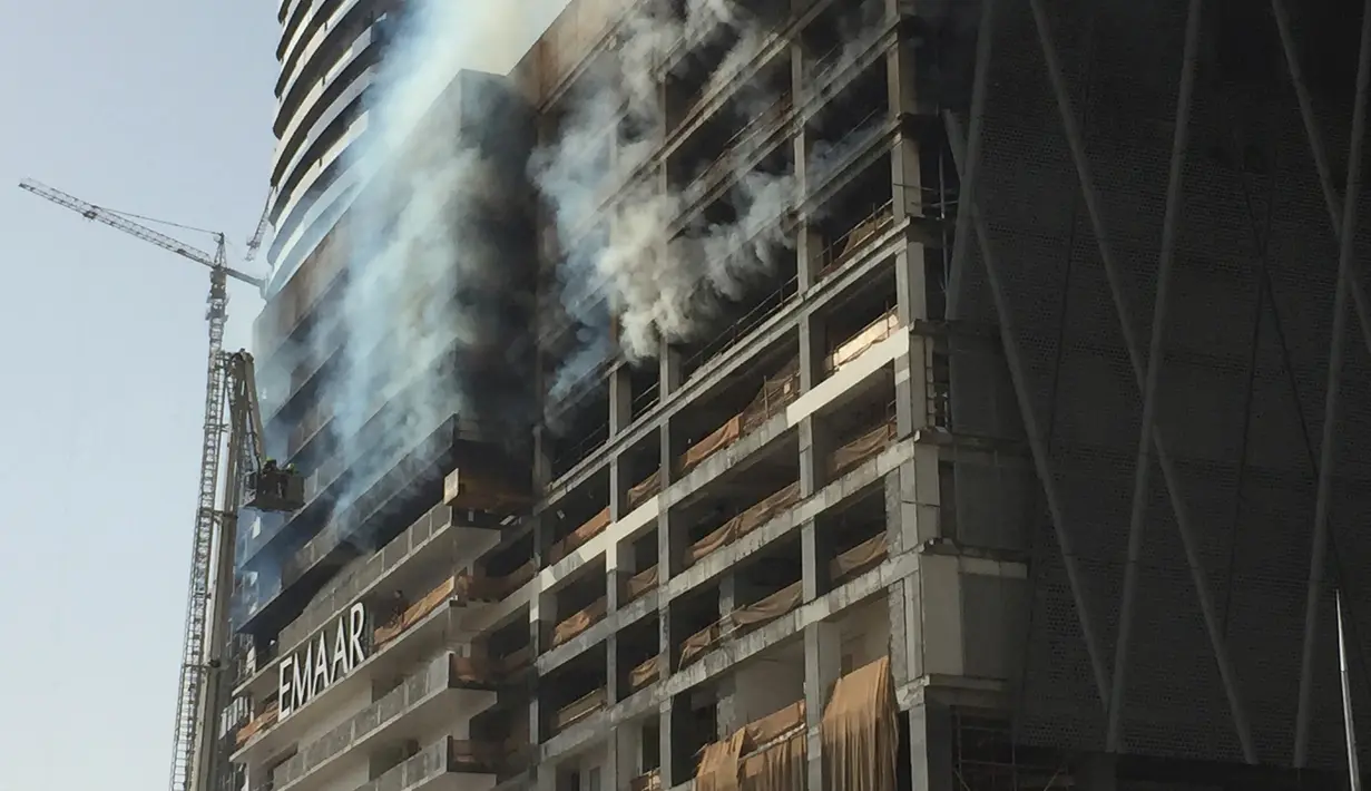 Petugas memadamkan api yang melanda sebuah gedung di sebelah Dubai Mall, Uni Emirat Arab, Minggu (2/4). Gedung yang terbakar diketahui sedang dikerjakan raksasa kontruksi Emaar. (AP Photo/ Jon Gambrell)